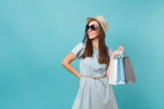 Moderne attraktive glückliche Frau des Porträts im Sommerkleid, Strohhut, Sonnenbrille, die Pakettaschen mit Käufen hält stockbild Moderne attraktive glückliche Frau des Porträts im Sommerkleid, Strohhut, Sonnenbrille, die Pakettaschen mit Käufen hält stockbild