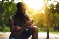 Moderno, um homem novo que usa um smartphone Adolescente afro-americano que guarda um smartphone móvel no por do sol fotos de stock Moderno, um homem novo que usa um smartphone Adolescente afro-americano que guarda um smartphone móvel no por do sol fotos de stock