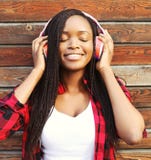 Modeståenden av den lyckliga le unga afrikanska kvinnan med hörlurar som tycker om, lyssnar till musik Royaltyfri Foto Modeståenden av den lyckliga le unga afrikanska kvinnan med hörlurar som tycker om, lyssnar till musik Royaltyfri Foto