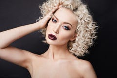 Modieuze modelvrouw met prachtige blauwe ogen en met blond krullend haar, met volledige lippen en professionele heldere make-up royalty-vrije stock fotografie Modieuze modelvrouw met prachtige blauwe ogen en met blond krullend haar, met volledige lippen en professionele heldere make-up royalty-vrije stock fotografie