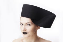 Modèle blond magnifique de femme avec les yeux bleus et le rouge à lèvres noir utilisant le casque unique de chapeau de grand noi photo libre de droits Modèle blond magnifique de femme avec les yeux bleus et le rouge à lèvres noir utilisant le casque unique de chapeau de grand noi photo libre de droits