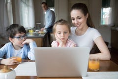 Moeder die beeldverhaal op computer voor kinderen tonen terwijl vader het koken stock fotografie Moeder die beeldverhaal op computer voor kinderen tonen terwijl vader het koken stock fotografie