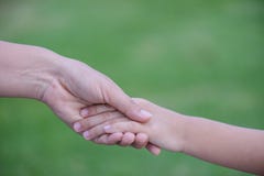 Moeder die een hand van zijn zoon met groene glasachtergrond houden royalty-vrije stock afbeeldingen Moeder die een hand van zijn zoon met groene glasachtergrond houden royalty-vrije stock afbeeldingen