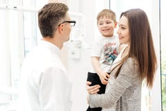 Moeder die haar zoon houden en aan tandarts in kliniek spreken Royalty-vrije Stock Afbeeldingen Moeder die haar zoon houden en aan tandarts in kliniek spreken Royalty-vrije Stock Afbeeldingen