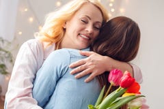 Moeder en dochter samen de viering die koesterend de tulpen van de mammaholding sloot thuis ogen bevinden zich royalty-vrije stock fotografie Moeder en dochter samen de viering die koesterend de tulpen van de mammaholding sloot thuis ogen bevinden zich royalty-vrije stock fotografie