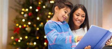 Moeder en dochterlezingsboek op Kerstmis stock afbeeldingen Moeder en dochterlezingsboek op Kerstmis stock afbeeldingen
