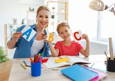 Moeder en kinddochter die en thuiswerk doen die thuis schrijven lezen stock foto Moeder en kinddochter die en thuiswerk doen die thuis schrijven lezen stock foto