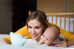 Moeder met haar pasgeboren babyzoon die op bed liggen stock fotografie Moeder met haar pasgeboren babyzoon die op bed liggen stock fotografie