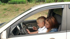 moederlijk expositie Voorstad Moeder Met Haar Zoon Die Een Auto Bestuurt, Moeder Laat Het Kind Zien Hoe  De Auto Werkt Stock Footage - Video of reis, meisje: 157531774