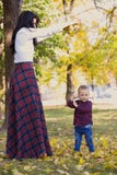 Moederspelen met haar zoon in het park in de herfst stock fotografie Moederspelen met haar zoon in het park in de herfst stock fotografie