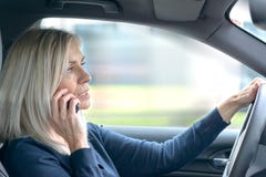 Mogen kvinna som pratar på hennes mobil i bilen royaltyfri bild Mogen kvinna som pratar på hennes mobil i bilen royaltyfri bild