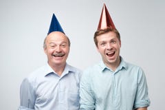 Mogen man och hans ung son som firar den lyckliga födelsedagen som bär roliga lock arkivbilder Mogen man och hans ung son som firar den lyckliga födelsedagen som bär roliga lock arkivbilder