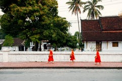 Moine marchant au vieux temple - tradition d'aumône de matin de Luang Prabang photo libre de droits Moine marchant au vieux temple - tradition d'aumône de matin de Luang Prabang photo libre de droits