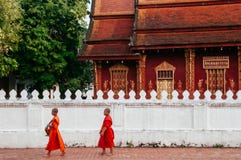Moine marchant au vieux temple - tradition d'aumône de matin de Luang Prabang images stock Moine marchant au vieux temple - tradition d'aumône de matin de Luang Prabang images stock