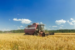Moissonneuse de cartel moderne travaillant au champ de ferme d'avoine sous le ciel bleu dans le jour d'été chaud photos libres de droits Moissonneuse de cartel moderne travaillant au champ de ferme d'avoine sous le ciel bleu dans le jour d'été chaud photos libres de droits