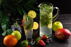 Mojito-Limonade in einem Krug und ein Glas und Früchte auf einem dunklen hölzernen Hintergrund lizenzfreie stockbilder Mojito-Limonade in einem Krug und ein Glas und Früchte auf einem dunklen hölzernen Hintergrund lizenzfreie stockbilder