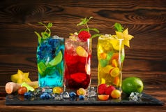 Mojitos azuis e amarelos frios Mojito vermelho com hortelã Mojito com rum Álcool em um fundo de madeira Bebidas e cocktail do ver fotografia de stock Mojitos azuis e amarelos frios Mojito vermelho com hortelã Mojito com rum Álcool em um fundo de madeira Bebidas e cocktail do ver fotografia de stock