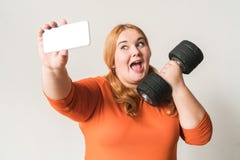 Mollige vrouwensport thuis status geïsoleerd op wit die selfie foto's met opgewekte domoor nemen stock foto's Mollige vrouwensport thuis status geïsoleerd op wit die selfie foto's met opgewekte domoor nemen stock foto's