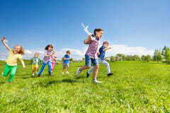 Molti bambini che corrono e giocattolo dell'aeroplano della tenuta del ragazzo fotografia stock Molti bambini che corrono e giocattolo dell'aeroplano della tenuta del ragazzo fotografia stock