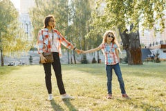 Mom and daughter holding hands walking in the park, golden hour royalty free stock photo Mom and daughter holding hands walking in the park, golden hour royalty free stock photo