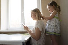 Mom and daughter are sitting by the window stock photo Mom and daughter are sitting by the window stock photo