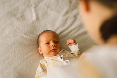 Mom Dresses Cute Newborn Little Baby Boy In A Jumpsuit. Royalty Free Stock Images