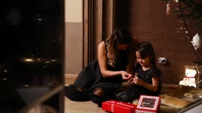 Mom and her daughter sit under a decorated Christmas tree at home consider gifts stock footage Mom and her daughter sit under a decorated Christmas tree at home consider gifts stock footage
