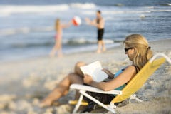 Mom reading in lounge chair on beach.