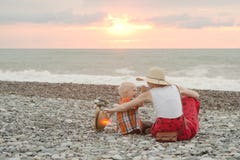 Mom and son play on the pebble beach. Sunset time. Back view royalty free stock photos Mom and son play on the pebble beach. Sunset time. Back view royalty free stock photos