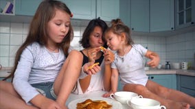Mom and two daughters eat pancakes