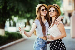 Moments positifs heureux de deux filles élégantes étreignant avec des cocktails sur la rue dans la ville Attarctive joyeux drôle photo libre de droits Moments positifs heureux de deux filles élégantes étreignant avec des cocktails sur la rue dans la ville Attarctive joyeux drôle photo libre de droits