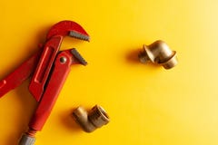 A monkey wrench on the yellow background with some fitting connectors. for design and decoration stock image A monkey wrench on the yellow background with some fitting connectors. for design and decoration stock image