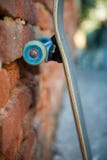 Monopatín que se inclina contra la pared hecha de ladrillos anaranjados Foto de archivo libre de regalías Monopatín que se inclina contra la pared hecha de ladrillos anaranjados Foto de archivo libre de regalías