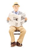 Monsieur supérieur sur une chaise en bois tenant un journal photos stock Monsieur supérieur sur une chaise en bois tenant un journal photos stock