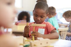 Montessori-Schüler, der am Schreibtisch mit hölzernen Formen arbeitet stockbilder Montessori-Schüler, der am Schreibtisch mit hölzernen Formen arbeitet stockbilder