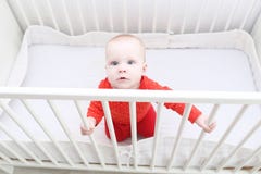6 month baby girl trying to get up in white bed Stock Photo 6 month baby girl trying to get up in white bed Stock Photo