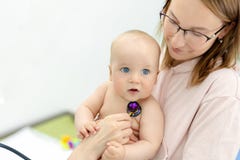 Monther holding baby on hands at doctors office. Pediatrician making examination of little cute infant boy with royalty free stock photos Monther holding baby on hands at doctors office. Pediatrician making examination of little cute infant boy with royalty free stock photos