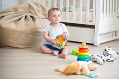 10 months old baby boy sitting on wooden floor at bedroom and playing with toys stock images 10 months old baby boy sitting on wooden floor at bedroom and playing with toys stock images