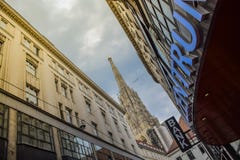 Vienna, Austria - September , 15, 2019: The Facade of a Shopping mall, a bank and a Vienna Cathedral tower at the stock photo Vienna, Austria - September , 15, 2019: The Facade of a Shopping mall, a bank and a Vienna Cathedral tower at the stock photo