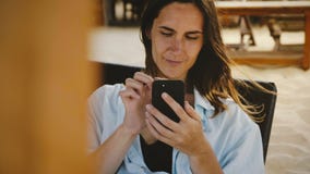 Mooi die close-up van gelukkige jonge onderneemster wordt geschoten die smartphonevermaak app gebruiken die op zitkamerligstoel g stock videobeelden Mooi die close-up van gelukkige jonge onderneemster wordt geschoten die smartphonevermaak app gebruiken die op zitkamerligstoel g stock videobeelden