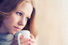 Mooi dromerig meisje met een kop van hete koffie bij het venster stock foto's Mooi dromerig meisje met een kop van hete koffie bij het venster stock foto's