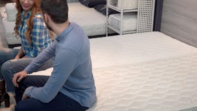 Mooi gelukkig paar die op comfortabele othopedic matras bij meubilairwinkel liggen stock footage Mooi gelukkig paar die op comfortabele othopedic matras bij meubilairwinkel liggen stock footage