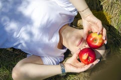 Mooi meisje die op het gras liggen De grappige stemming, behandelde haar gezicht met appelen stock fotografie Mooi meisje die op het gras liggen De grappige stemming, behandelde haar gezicht met appelen stock fotografie