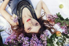Mooi meisje in kleding stellen die in lilac takken op een de zomerdag, purpere bloemen in het Park liggen De lenteportret van het stock fotografie Mooi meisje in kleding stellen die in lilac takken op een de zomerdag, purpere bloemen in het Park liggen De lenteportret van het stock fotografie