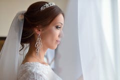 Mooie bruid in witte huwelijkskleding die zich in haar slaapkamer bevinden en in venster kijken, wacht zij op de bruidegom stock foto's Mooie bruid in witte huwelijkskleding die zich in haar slaapkamer bevinden en in venster kijken, wacht zij op de bruidegom stock foto's