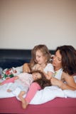 Mooie gelukkige familiescène met moeder die aan haar weinig dochter met haar pop spreken Royalty-vrije Stock Foto's Mooie gelukkige familiescène met moeder die aan haar weinig dochter met haar pop spreken Royalty-vrije Stock Foto's