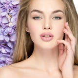 Mooie jonge blondevrouw met bloemen dichtbij gezicht stock fotografie Mooie jonge blondevrouw met bloemen dichtbij gezicht stock fotografie
