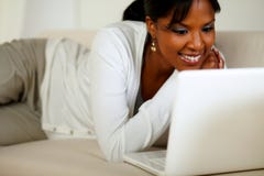 Mooie jonge vrouw die en aan laptop glimlacht kijkt royalty-vrije stock foto's Mooie jonge vrouw die en aan laptop glimlacht kijkt royalty-vrije stock foto's