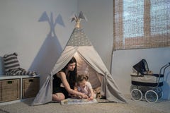 Mooie moeder die aan dochter in een tipi lezen royalty-vrije stock afbeelding Mooie moeder die aan dochter in een tipi lezen royalty-vrije stock afbeelding