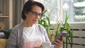 Mooie rijpe vrouw die in glazen koffie drinken stock footage Mooie rijpe vrouw die in glazen koffie drinken stock footage